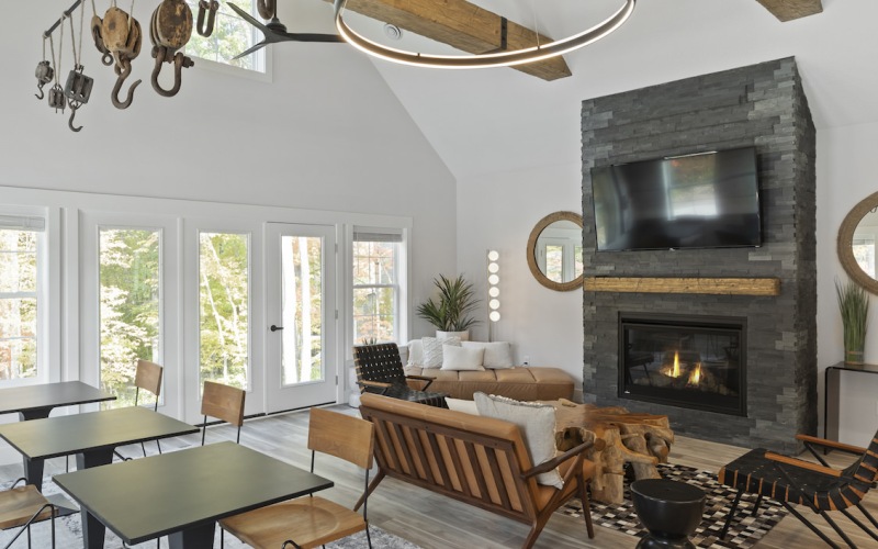 Club room with fireplace, lounge seating, and cafe tables connected to pool and outdoor entertainment